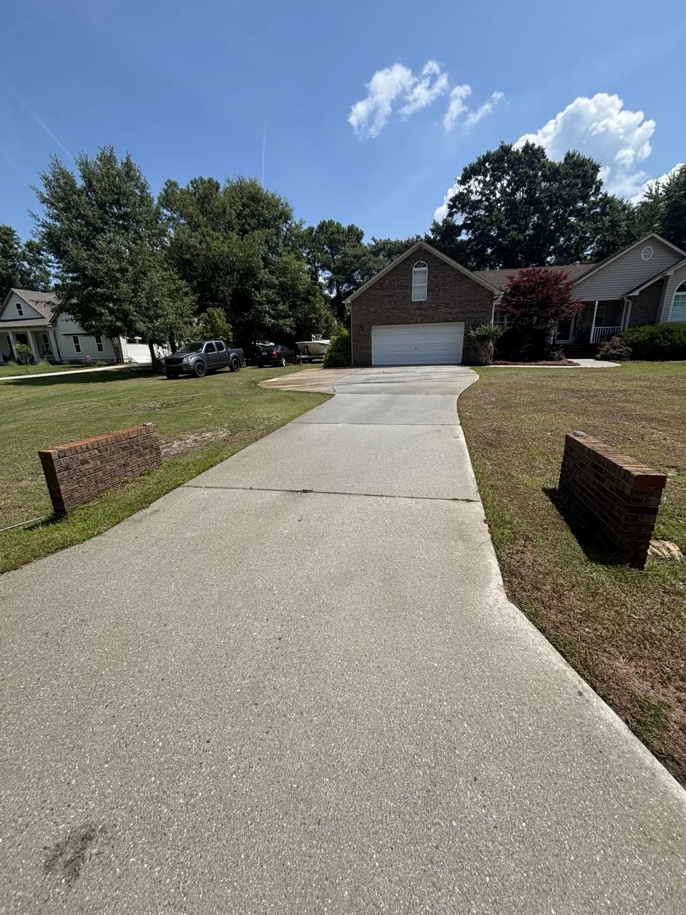 A long residential driveway cleaned end to end, running back to the garage between brick pillars